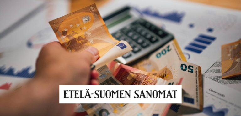 Henkilön kädessä käteistä ja pöydällä laskin