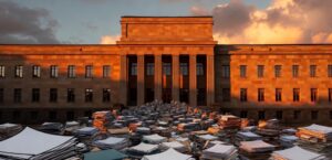 Hovioikeuksien ruuhka – suuri paperikasa hovioikeusrakennuksen edessä symboloi kasvavaa juttumäärää ja pitkittyneitä käsittelyaikoja Suomessa